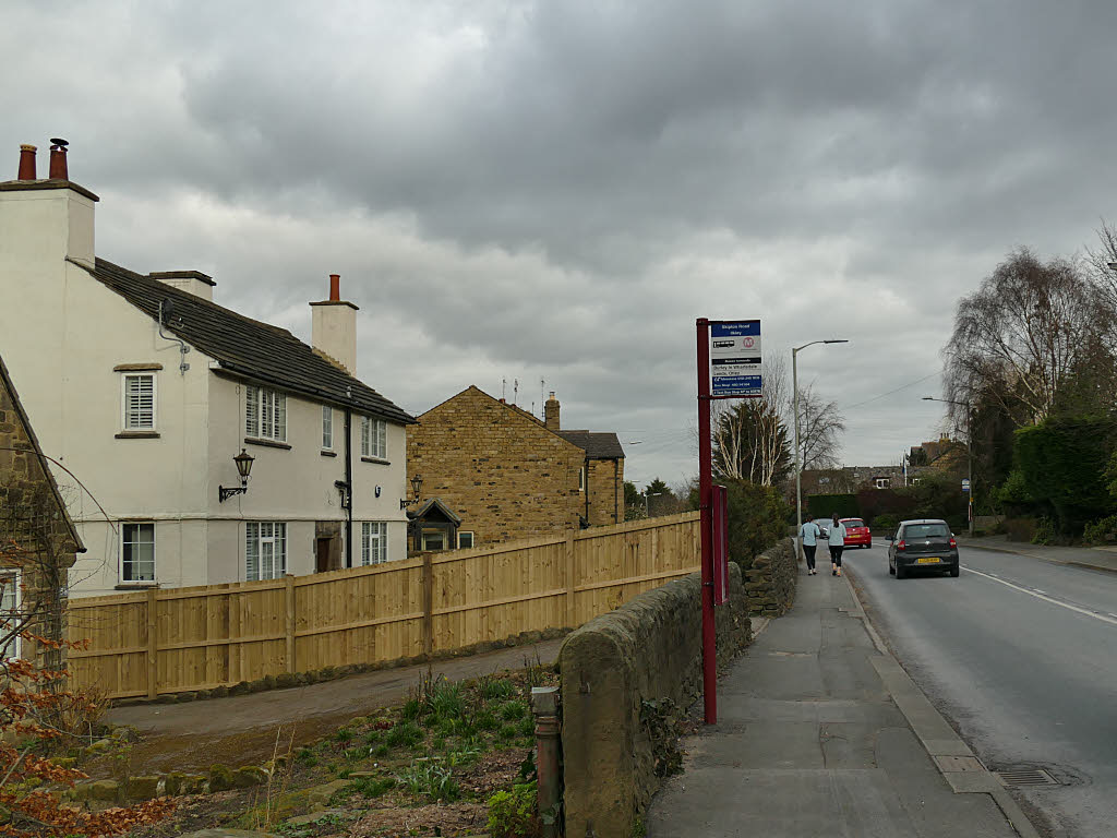 Skipton Road, the A65, at the Victoria Avenue bus stops beside the site, a two-lane road with a stone wall
